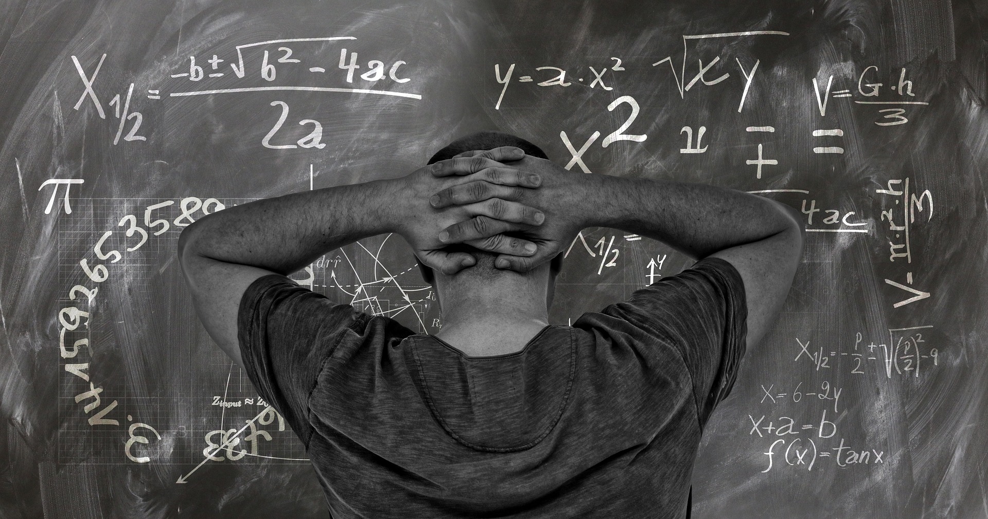 Physics Board A man standing in front of a blackboard with formulas